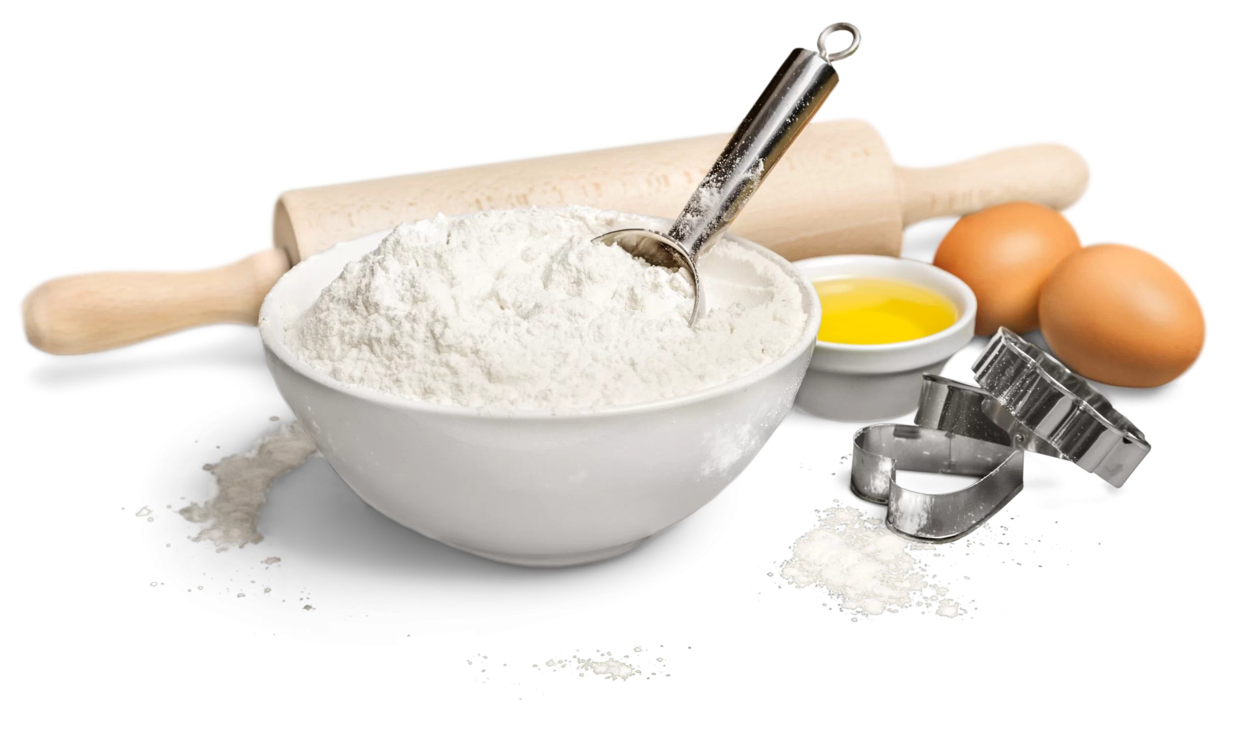 Bowl of flour with a scoop, rolling pin, eggs, and heart-shaped cookie cutters on a white background.